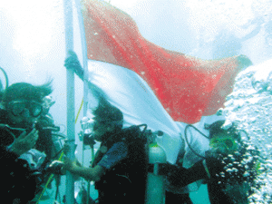 Para peserta upacara mendekati tiang bendera seusai upacara bendera peringatan detik-detik Proklamasi di bawah laut, yang diikuti 2.486 penyelam, di pantai Malalayang, Manado, Sulawesi Utara, Senin (17/8).